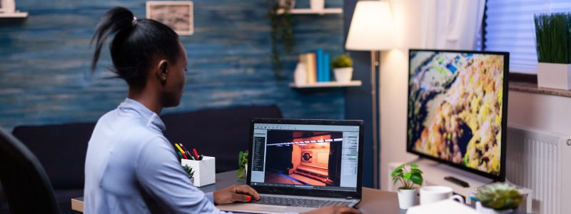 Young african woman gamer testing online professional game on laptop at home late at night. Professional player checking digital video games on her computer with modern technology network wireless.